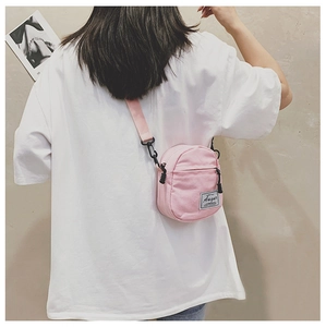 Pink canvas mini crossbody bag with Augur label shown in a lifestyle model shot