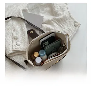Internal view of cream bucket bag showing spacious storage for phone, wallet and perfume