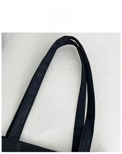 Detailed close-up of durable black canvas tote bag handles with reinforced stitching