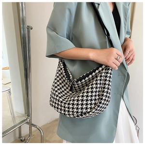 Detail of checkered hobo crossbody bag with houndstooth pattern and black strap