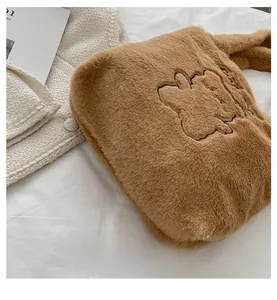 Gros plan détaillé du sac cabas en peluche marron avec broderie cartoon et texture douce