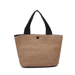 Natural woven straw beach tote bag with black fabric handles and snap closure