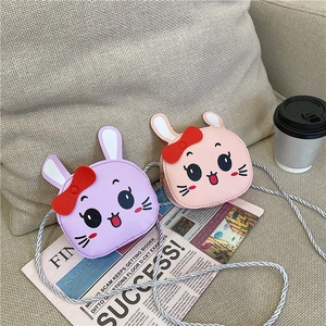 Detail of pink and purple cartoon rabbit crossbody bags with 3D ears on a sofa