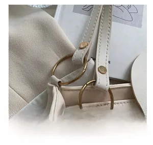 Detail of gold metal ring and heart embossed texture on cream leather tote bag