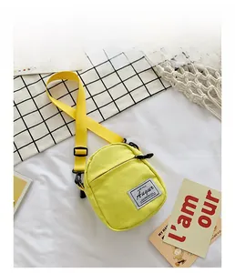 Detail view of mini yellow canvas crossbody bag with adjustable strap and brand label