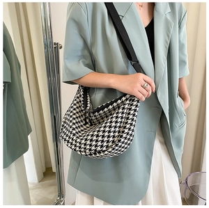 Detail of checkered crossbody crescent bag featuring wide adjustable strap and zipper close