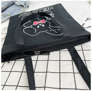Detail showing the smooth metal zipper closure on this black canvas tote bag