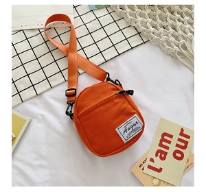 Top view of mini orange canvas crossbody bag with adjustable wide strap and Augur label