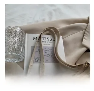 Detail of cream white tote bag featuring embossed pattern and gold metal ring hardware