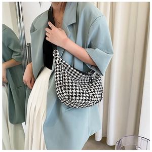 Detail of checkered crescent crossbody bag with black wide strap and metal zipper