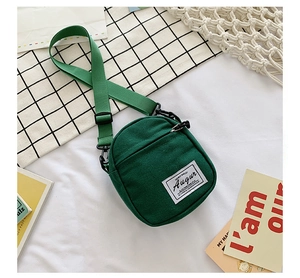 Detail of green canvas crossbody bag showing durable fabric and adjustable shoulder strap