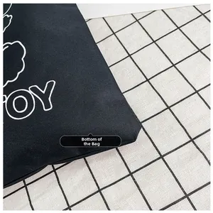 Detailed view showing the durable canvas material and stitched bottom of the black tote bag