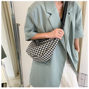 Close-up of houndstooth half-moon crossbody bag with adjustable black nylon strap