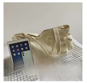 Detailed view of cream corduroy tote bag showing large capacity vs iPad and iPhone