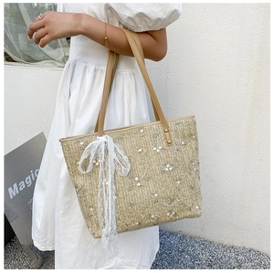 Detail of summer straw tote with white flower embroidery and lace ribbon accessory