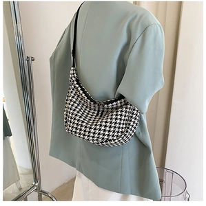 Detail of checkered crossbody bag with metal dual zippers and black adjustable strap