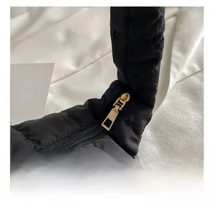 Detail of smooth gold zipper on black quilted nylon bag with puffy square texture