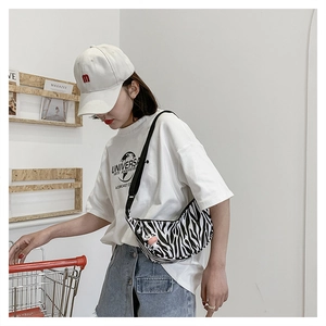 Detail of zebra print crescent crossbody bag with adjustable strap and cute cow charm