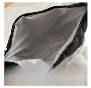 Detail view of spacious light gray interior and zipper closure of the black quilted bag