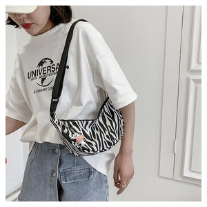 Detail of zebra pattern nylon crescent bag with wide strap and cute cow pendant