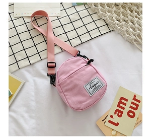 Detailed macro shot of the pink mini canvas crossbody bag with adjustable strap and brand tag