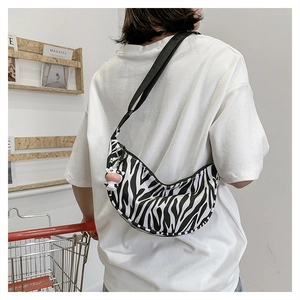 Close-up of zebra print nylon crescent bag with adjustable strap and cute cow pendant