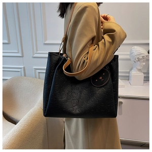 Detail of the black tote bag featuring embossed cartoon patterns and brown PU handles