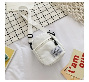 Detail of white canvas crossbody bag with front zipper pocket and adjustable strap