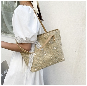 Detail of hand-woven straw tote with white flower embroidery and lace ribbon accents