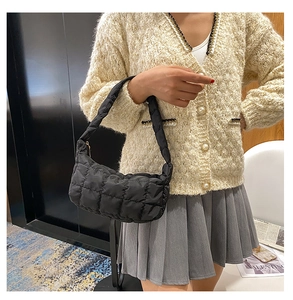 Detail of a black quilted shoulder bag with soft nylon padding and pleated square stitching