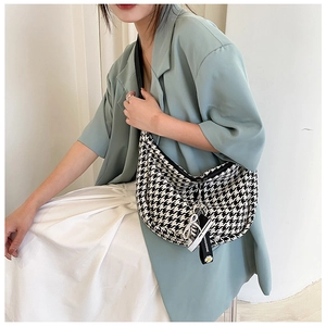 Detail of checkered crescent bag with mini sneaker charm and decorative brand strap