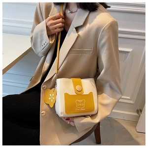 Detail showing the wood buckle and bear print on the yellow contrast bucket bag