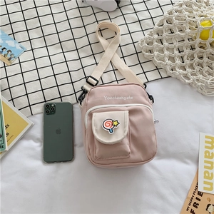 Detail of pink canvas crossbody bag with lollipop patch and white contrast pocket