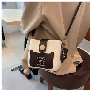 Detail of printed bucket bag featuring a bear pattern and a wooden button closure