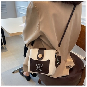 Detail of crossbody bucket bag featuring a cartoon bear print and stylish wooden buckle