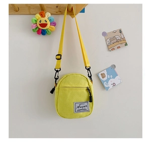 Detail of yellow canvas mini crossbody bag with Augur brand patch and adjustable strap