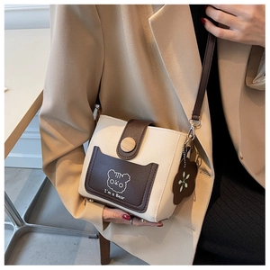 Detail of flower charm and bear print on off-white bucket bag with brown accents