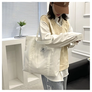 Detail einer cremefarbenen Cord-Tasche mit Blatt-Patch und breiten Schultergurten in Nahaufnahme