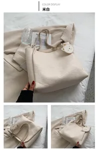 Detail of cream white tote bag with embossed cartoon patterns and cute cat charm