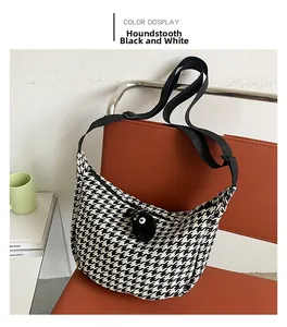 Detail of checkered crossbody bag with black plush charm on a modern chair