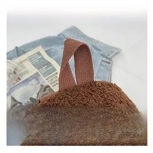 Close-up of the reinforced fabric handle and smooth zipper on brown fleece backpack