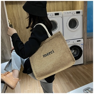 Detail of high-capacity canvas tote bag with merci lettering and thick cotton shoulder straps