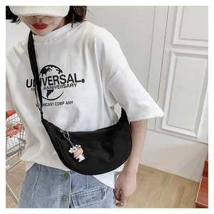 Detail of black canvas crescent bag with adjustable strap and cute cow keychain