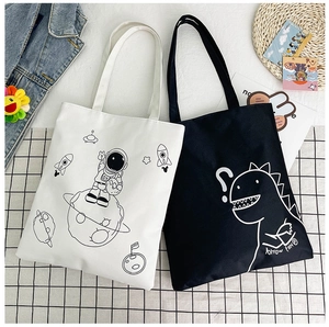 Detailed flat lay of canvas tote bags with astronaut and dinosaur line art prints