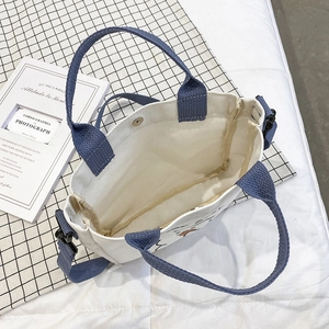 White canvas tote with blue straps and artistic line drawing, showing interior view