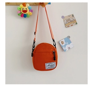 Close-up of bright orange canvas crossbody bag with Augur brand label and front zipper