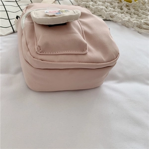 Detailed close-up of a pink crossbody bag featuring a lollipop charm and canvas texture