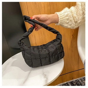 Detail of black quilted puffer hobo bag with a soft texture and seamless handle