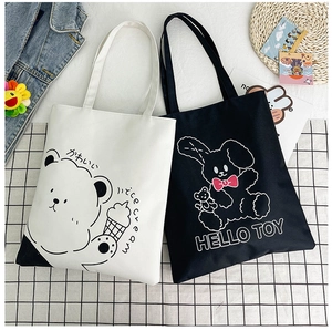 Flat lay of black and white canvas tote bags with cute cartoon bear and rabbit prints