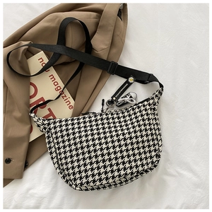 Detail of checkered crescent bag with adjustable strap and decorative mini shoe charm